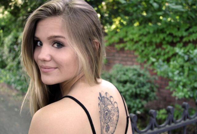 Smiling young blonde woman with large tattoo on her back considering tattoo removal in Baton Rouge